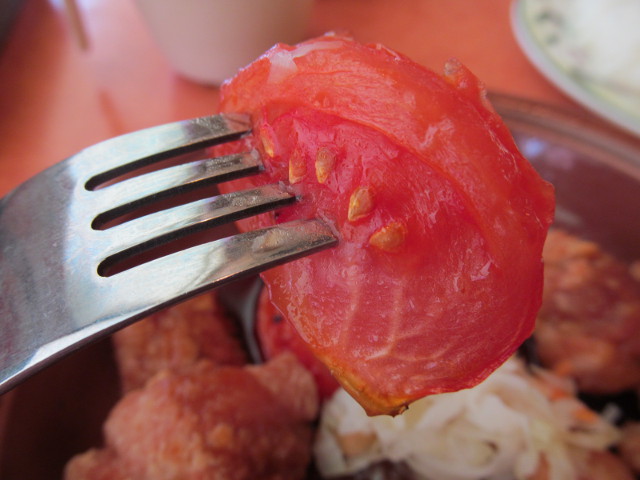 サイゼリヤ鶏肉のオーブン焼きのトマトを持ち上げる